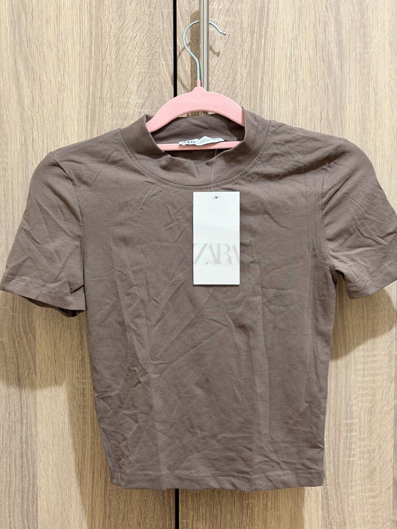Zara Brown Short Sleeve Crop Top (Category: Shirts) located in Manila. Submitted by anj_1414 (Listing ID 1466768311, Image 1). Description: - Brand: Zara - Size: Small can fit up to Medium - Color: Brown (Great neutral piece) - Fit: Slim fit with high neckline and short sleeves - Material: Soft, stretchy cotton - Styling: Perfect to pair with high-waisted jeans or skirts.