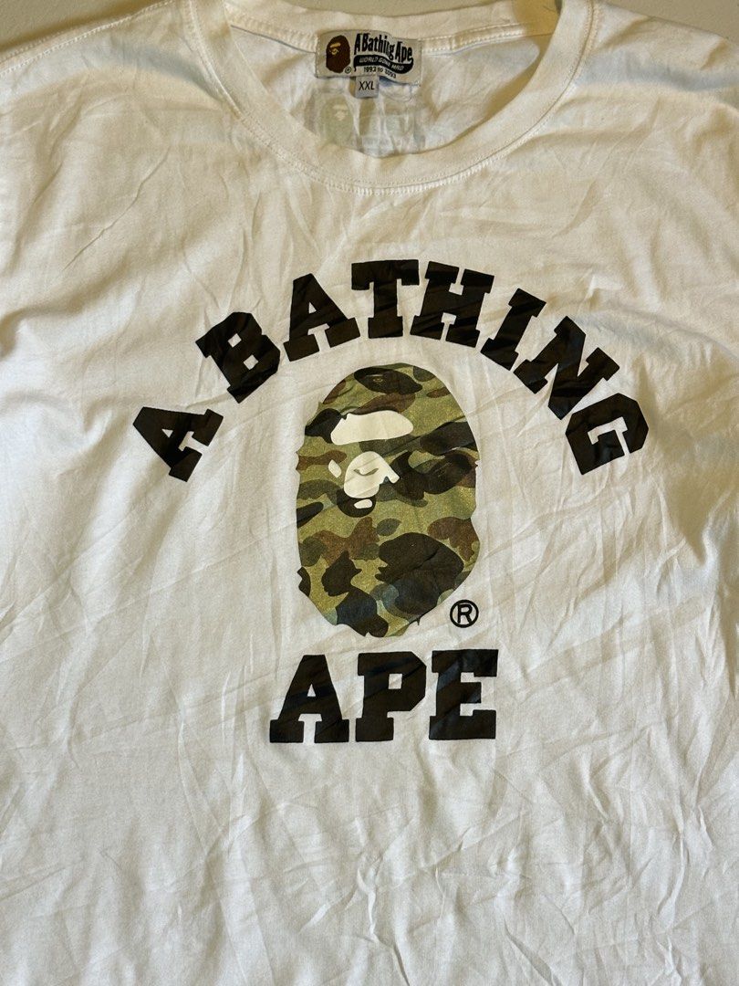 A Bathing Ape Bape Camo Logo Tee White XXL (Category: Tshirts & Polo Shirts ) located in Cavite. Submitted by remcadzzz (Listing ID 1466895424, Image 2). Description: - Brand: A Bathing Ape (Bape) - Color: White - Size: XXL (Tag at collar) - Design: Classic camo ape head logo with 'A Bathing Ape World Gone Mad 1993 to 2093' text - Details: Signature sleeve tag on the left arm, crew neck cut - Condition: Clean fabric, great for everyday streetwear
