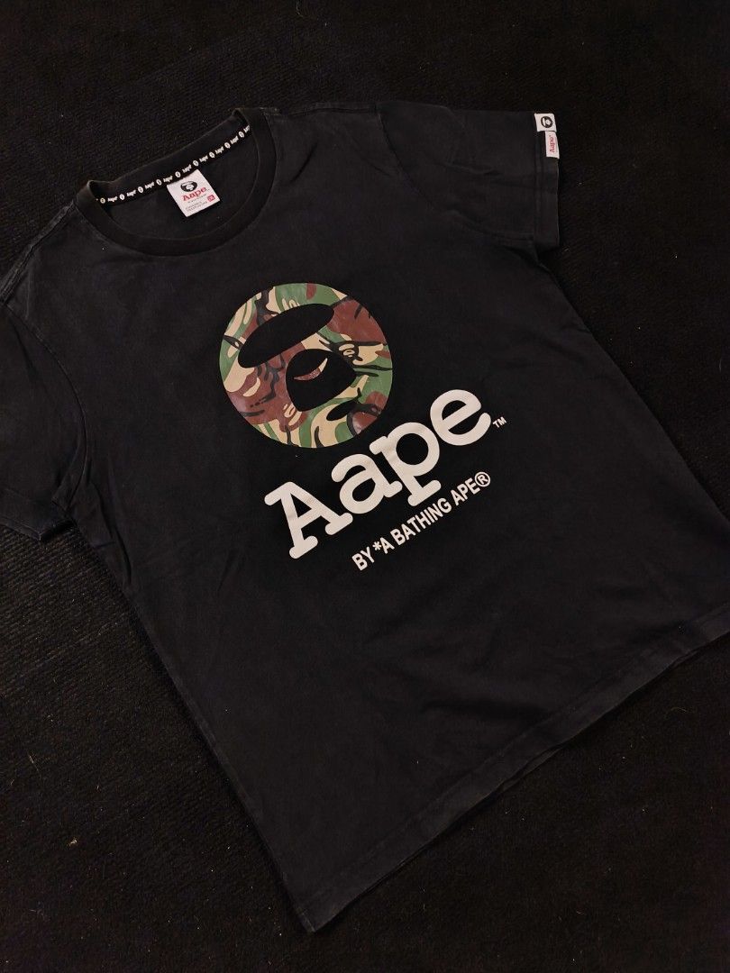 Aape CAMOU (Category: Tshirts & Polo Shirts ) located in San Fernando. Submitted by gaboo_asncn (Listing ID 1466905529, Image 1). Description: - Aape CAMOU - Size: 2XL on tag (W21/L26) - Condition: Excellent - Color Rate: 8.5/10 - No issue Take note: The shirt is black, and since the carpet/background is also black, the color may look slightly faded or less vibrant in the photos. In actual lighting, the shirt has a normal black color..