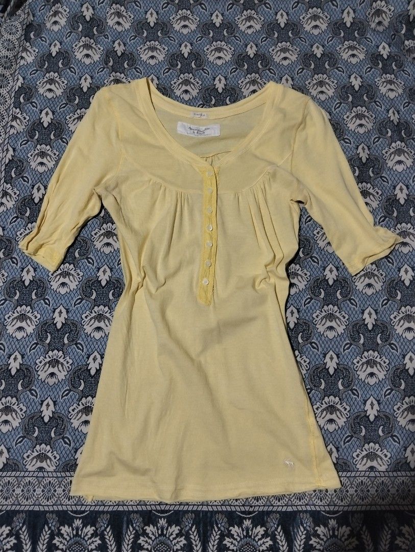 Abercrombie & Fitch Stretch Yellow Button-Front Top (Category: Blouses) located in Sibulan. Submitted by paulbrain (Listing ID 1466906619, Image 1). Description: - Brand: Abercrombie & Fitch - Size: Medium Width 15 x Length 26.6 - Color: Vibrant Yellow - Material: 90% Cotton, 10% Elastane (Stretch blend) - Design: Button-front placket, scoop neckline, and 3/4 sleeves - Detail: Signature embroidered moose logo near the bottom hem - Origin: Made in