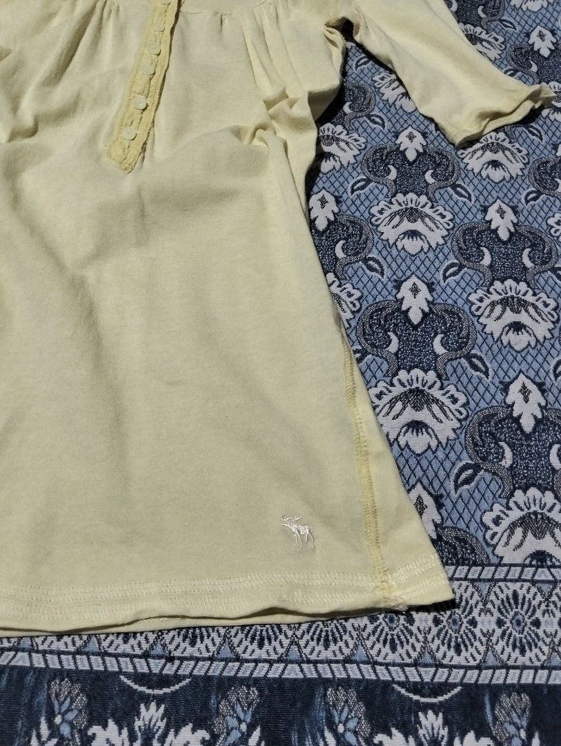 Abercrombie & Fitch Stretch Yellow Button-Front Top (Category: Blouses) located in Sibulan. Submitted by paulbrain (Listing ID 1466906619, Image 3). Description: - Brand: Abercrombie & Fitch - Size: Medium Width 15 x Length 26.6 - Color: Vibrant Yellow - Material: 90% Cotton, 10% Elastane (Stretch blend) - Design: Button-front placket, scoop neckline, and 3/4 sleeves - Detail: Signature embroidered moose logo near the bottom hem - Origin: Made in