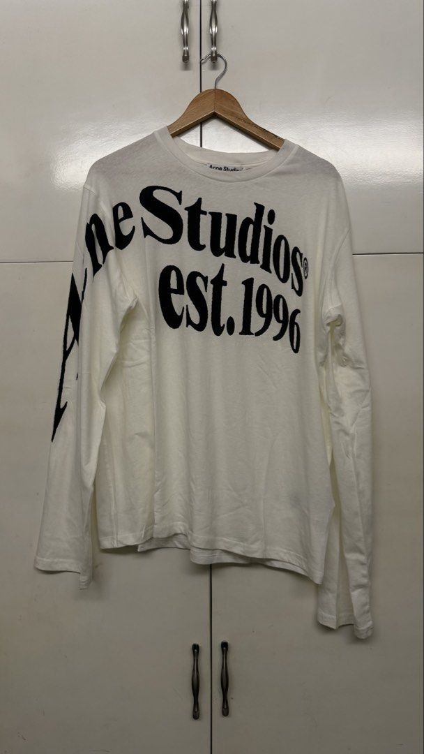 Acne Studios Long Sleeve White T-Shirt Size S (Category: Coats, Jackets and Outerwear) located in Calamba. Submitted by migsdeclutter (Listing ID 1466845928, Image 1). Description: - Brand: Acne Studios - Item: White long-sleeve tee with striking black logo print wrapping around the sleeve - Size: S Runs Big 25 x 29 - Material: Premium clean white cotton - Authenticity: Interior care tags and QR code tag attached - Condition: Excellent, well-main