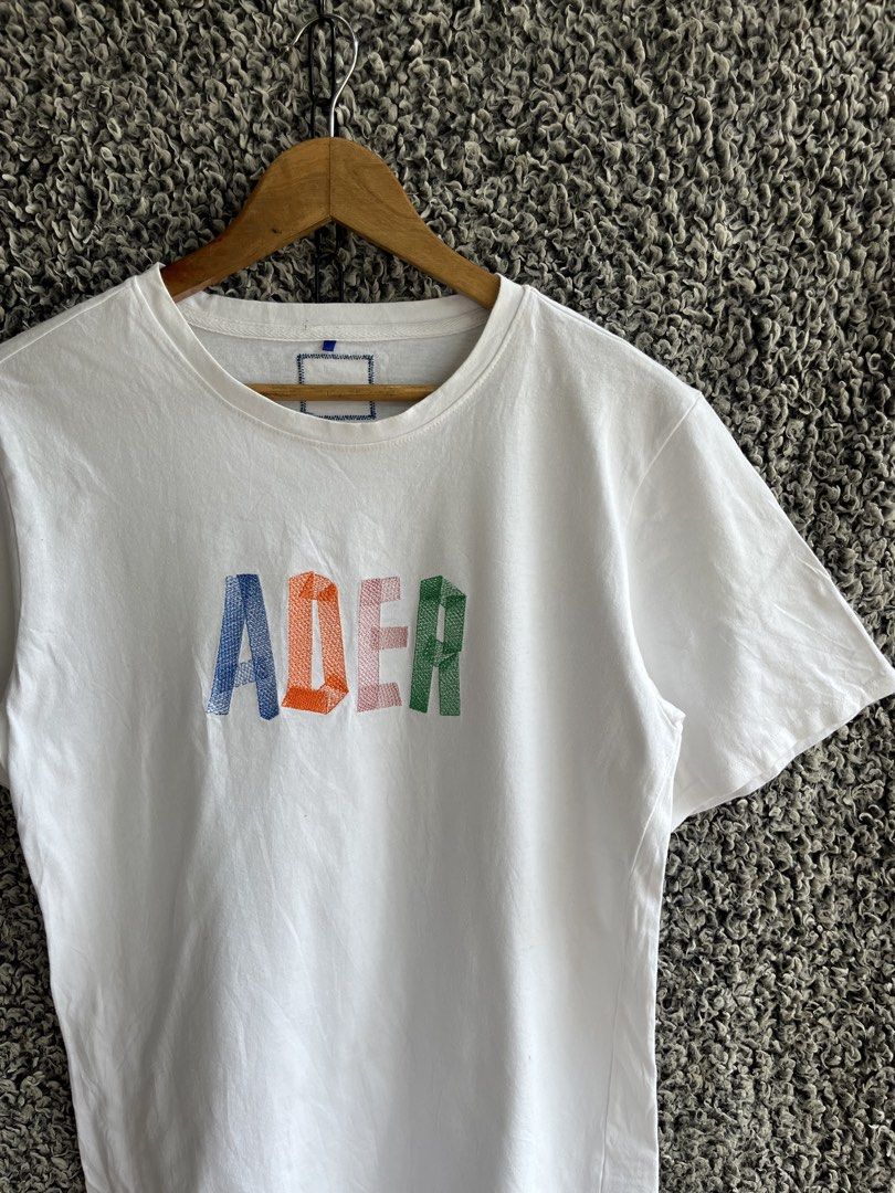 Ader Error Embroidered Logo Tee | Size M to L (Category: Shirts) located in General Trias. Submitted by zrchustle.604 (Listing ID 1466823357, Image 2). Description: Ader Error Embroidered Logo Tee featuring a distinctive multi-color textured logo graphic across the chest. • Design: Short-sleeve cotton crewneck t-shirt in white with a colorful embroidered "ADER" block letter graphic on the front. • Details: Features the signature multi-colored emb