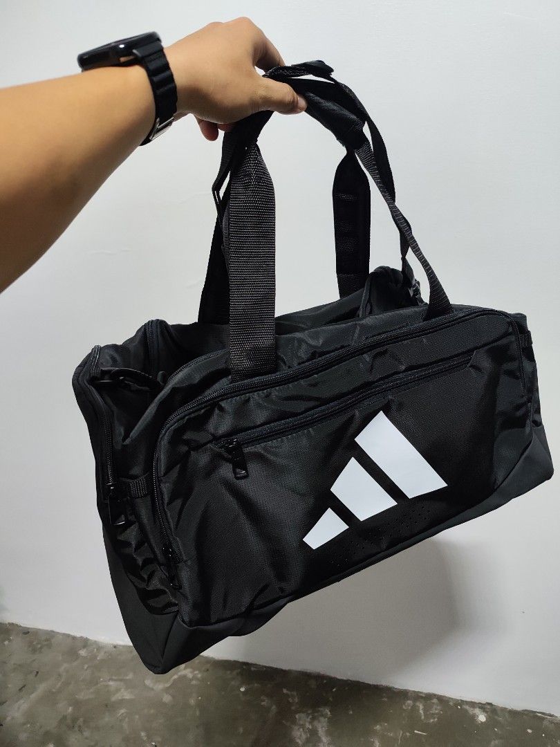Adidas Black Duffel Bag Gym Bag (Category: Sling Bags) located in Manila. Submitted by mikegoods.ph (Listing ID 1466890465, Image 2). Description: - Authentic Black Adidas Gym Duffel Bag - Large main compartment for all your workout gear - Front zip pocket for easy access to smaller essentials - Dual carry handles and an Adidas-branded padded shoulder strap - Durable material with a reinforced base panel for extra toughness - Ideal for gym sessio
