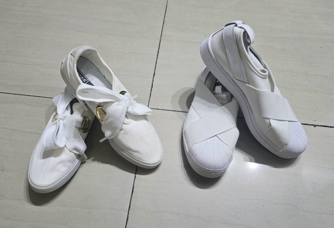 Adidas White Slip-On Sneaker Bundle (Category: Sneakers) located in Manila. Submitted by brandedshoppe_mnl (Listing ID 1466924260, Image 1). Description: 100% Original adidas sneakers -Unused/Shoes only, no box -Two pairs of white Adidas slip-on sneakers. One pair has thick laces tied in big bows with gold hardware accents. The other pair features wide elastic cross straps over the top and shell toes. -Both are size US 8, clean white canvas and r