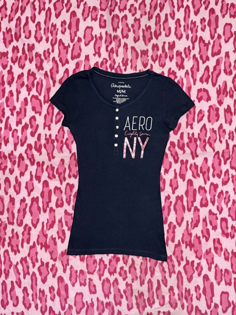 Aeropostale Henley Navy Blue (Category: Blouses) located in Cagayan de Oro. Submitted by _wh0reforjuicy (Listing ID 1466968489, Image 1). Description: - Brand: Aeropostale - Size: Small to Medium MM on tag - Color: Dark blue with white 'AERO' and sparkly pink 'NY' print - Details: Short sleeves, scoop neckline, button-up front accent - Flaw: Small hole near the bottom hem area - Perfect for casual everyday wear!.