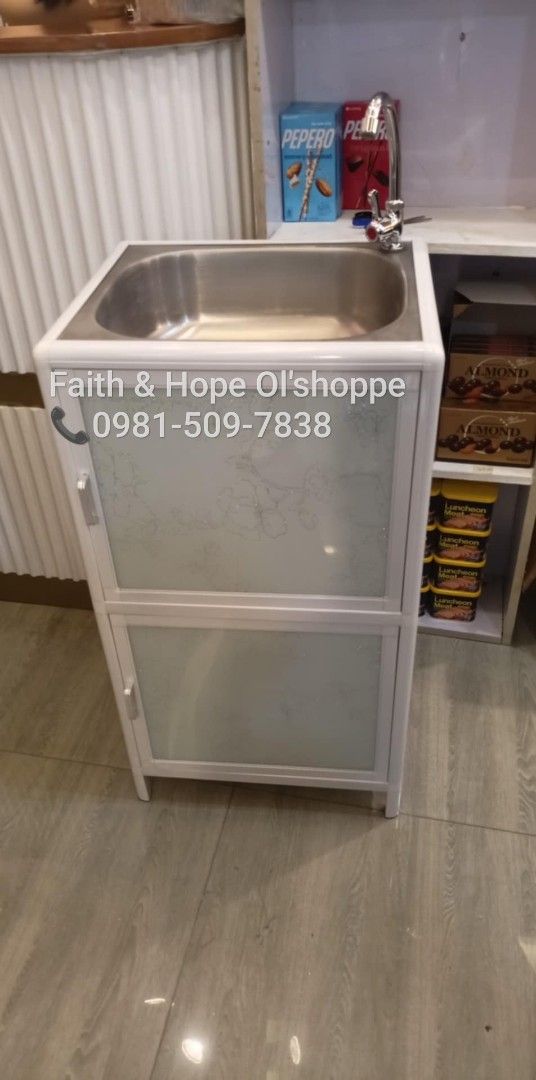 Aluminum Kitchen Sink Cabinet With Storage (Category: Bathroom & Kitchen Fixtures) located in Manila. Submitted by jamfrimzy089458 (Listing ID 1466828377, Image 2). Description: - Dimensions: 46cm (L) x 40cm (W) x 83cm (H) - Durable aluminum frame in white with stylish frosted glass doors and floral pattern - Includes stainless steel basin, faucet, and complete plumbing set - Features double-tier interior storage and a convenient open bottom shel