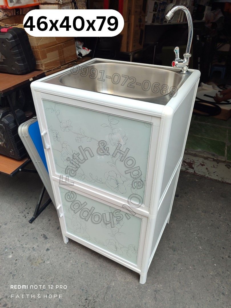 Aluminum Kitchen Sink Cabinet With Storage (Category: Bathroom & Kitchen Fixtures) located in Manila. Submitted by jamfrimzy089458 (Listing ID 1466828377, Image 3). Description: - Dimensions: 46cm (L) x 40cm (W) x 83cm (H) - Durable aluminum frame in white with stylish frosted glass doors and floral pattern - Includes stainless steel basin, faucet, and complete plumbing set - Features double-tier interior storage and a convenient open bottom shel
