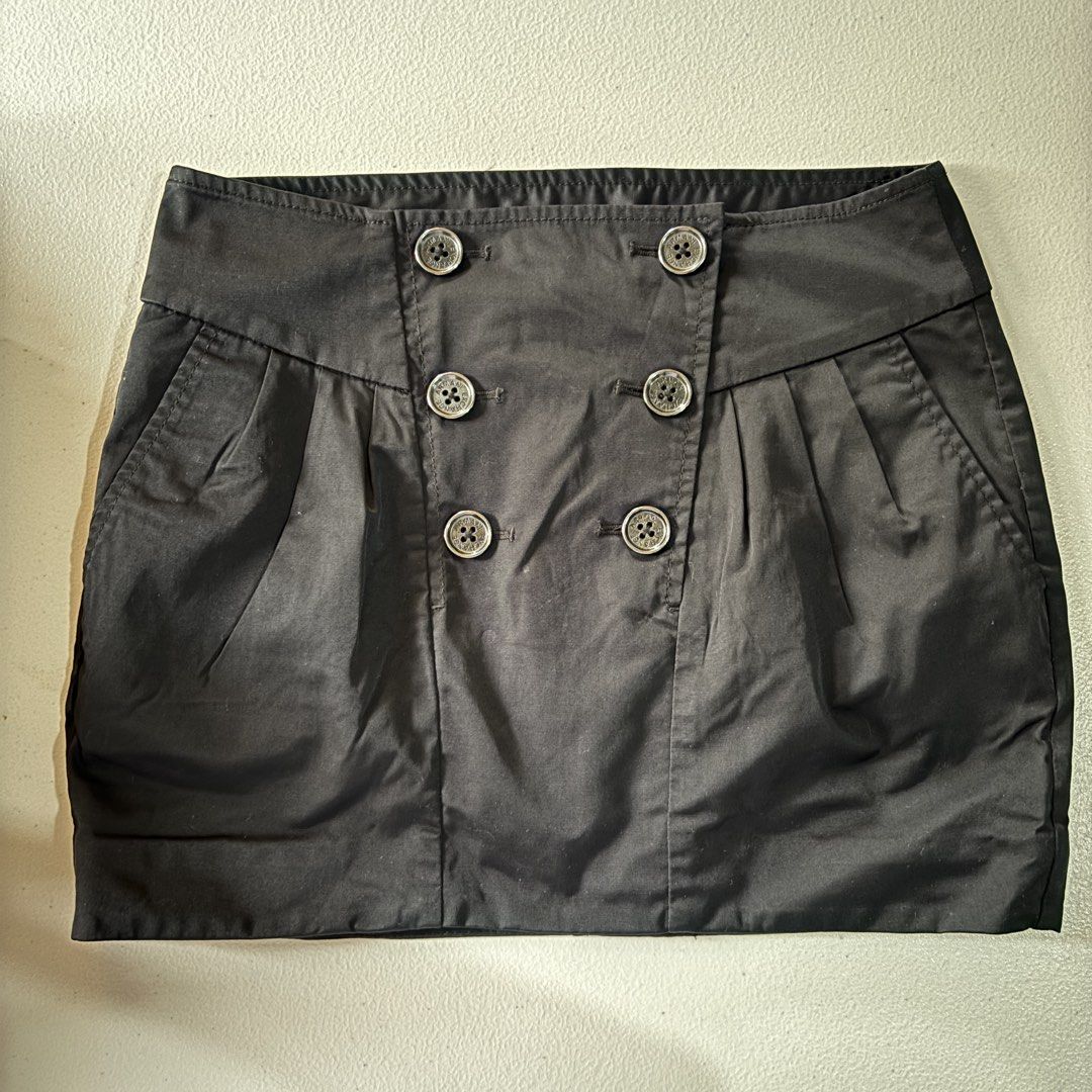 Armani Exchange Black Double-Breasted Mini Skirt Size 0 (Category: Skirts) located in Guimba. Submitted by huenited (Listing ID 1466843889, Image 1). Description: - Brand: Armani Exchange - Color: Black - Size: 0 - Style: Mini skirt with double-breasted front and pleated front pockets - Details: Metallic branded buttons, structured waistband, crisp fabric - Origin: Made in China - Condition: Excellent pre-loved condition.