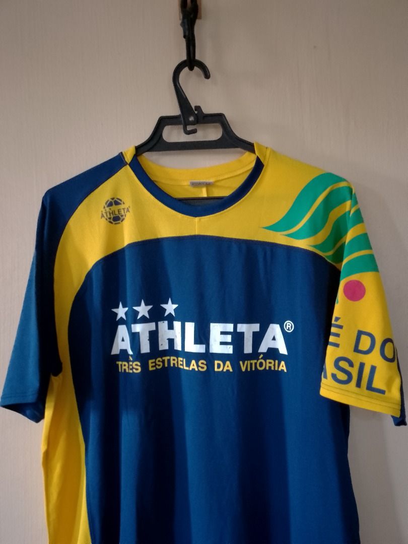 Athleta Três Estrelas Da Vitória Jersey (Category: Activewear) located in Bayombong. Submitted by daily10 (Listing ID 1466875906, Image 3). Description: - Est Size: O (XL) - Dimensions: 23" x 29f" x 31b" - Authentic Athleta soccer jersey in classic blue with striking yellow and green accents - Features bold 'ATHLETA' and 'TRÊS ESTRELAS DA VITÓRIA' chest branding - Detailed with 'CAFE DO BRASIL' text and green wave graphics on the sleeves - Comfor