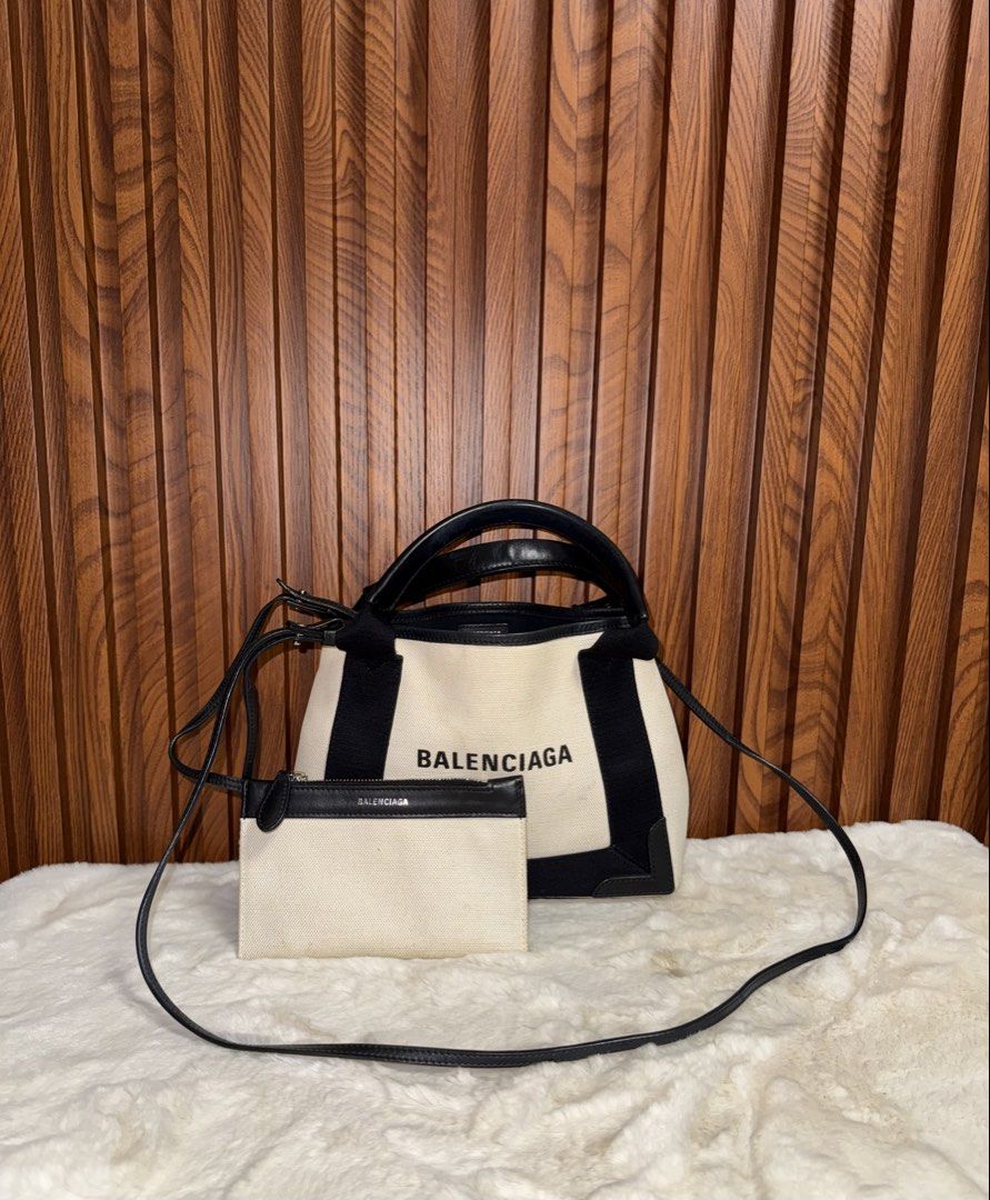 Authentic Balenciaga Navy Cabas Canvas Tote Bag (Category: Tote Bags) located in Subic. Submitted by luxshoppe88 (Listing ID 1466876458, Image 1). Description: - Authentic Balenciaga Navy Cabas Tote - Color: Cream canvas with black leather trim - Includes detachable matching zippered pouch - Dual top handles and long shoulder strap - Black interior lining with leather brand patch - Condition: Minor wear and scuffs on the base, with some faint dis