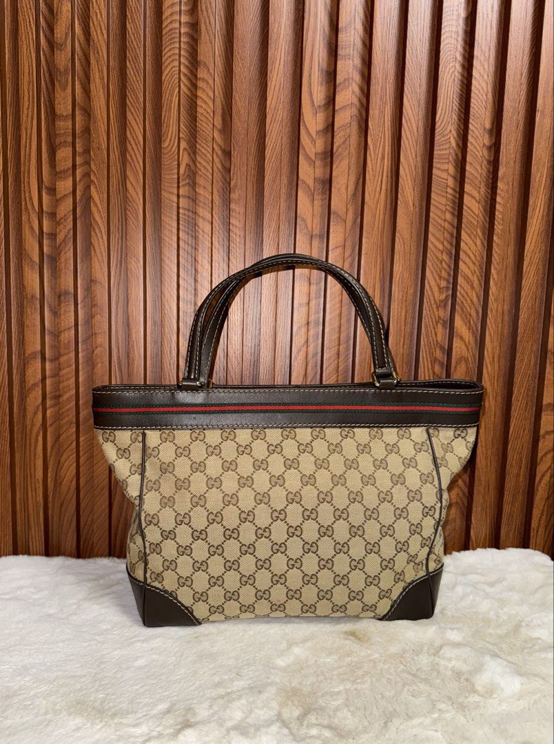 Authentic Gucci GG Canvas Web Stripe Tote Bag Brown (Category: Tote Bags) located in Subic. Submitted by luxshoppe88 (Listing ID 1466874380, Image 3). Description: Authentic classic Gucci tote in beige and ebony GG canvas with dark brown leather trim, signature red and green web stripe, and a charming gold-toned bow. Features dual shoulder straps, magnetic snap closure, and a spacious cream fabric interior with a zip pocket. Made in Italy. A time