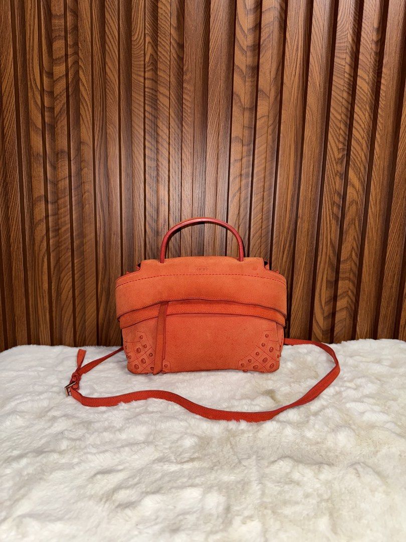 Authentic Tod's Orange Suede Crossbody Bag (Category: Luxury Bags & Wallets) located in Subic. Submitted by luxshoppe88 (Listing ID 1466875126, Image 1). Description: - Brand: Tod's - Material: Bright orange suede with silver hardware - Condition: Clean inside and out, well maintained - Features: Top handle, detachable shoulder strap, secure top zip closure - Details: Signature rubber pebbles on bottom corners, black fabric interior lining - Orig