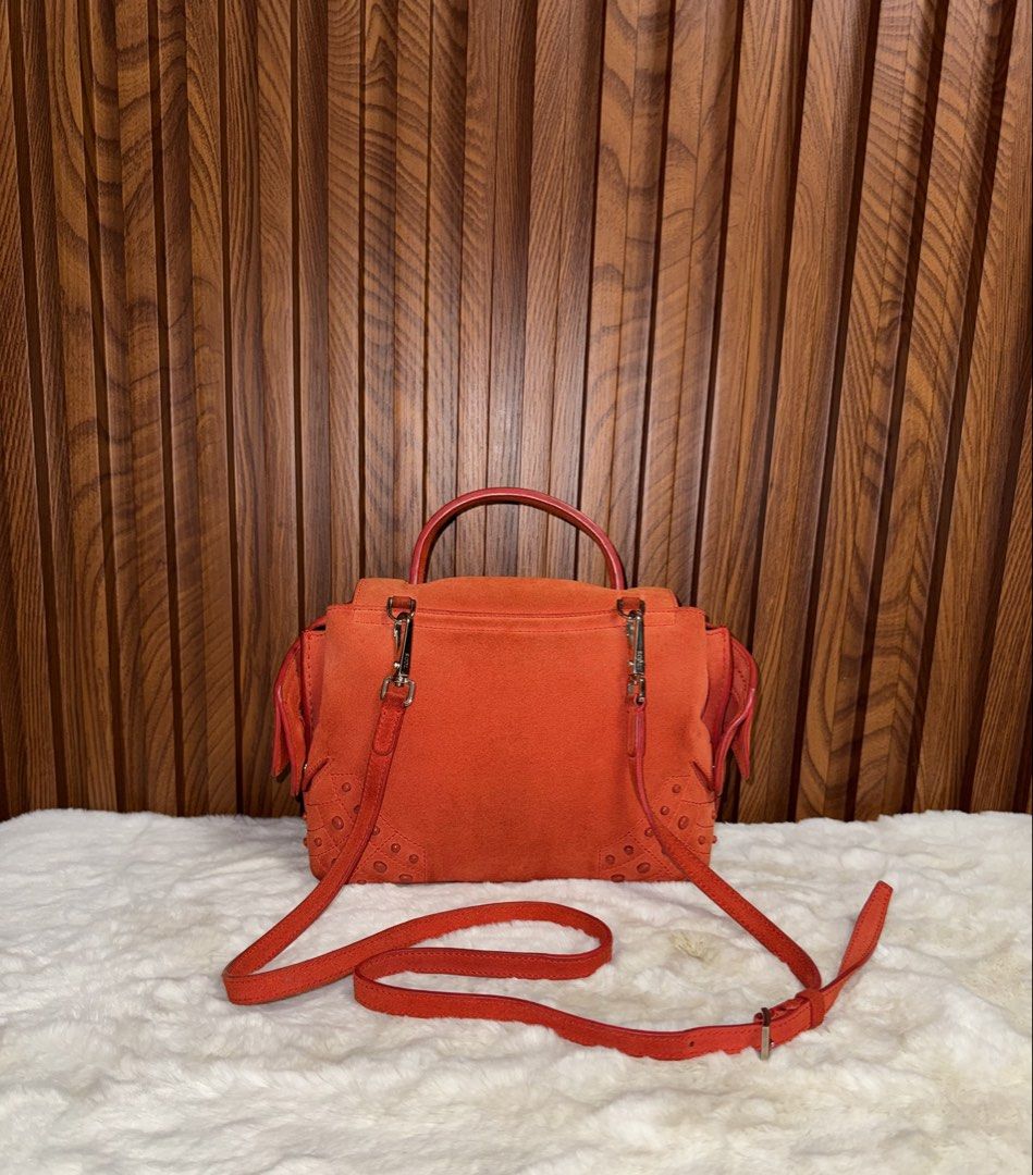 Authentic Tod's Orange Suede Crossbody Bag (Category: Luxury Bags & Wallets) located in Subic. Submitted by luxshoppe88 (Listing ID 1466875126, Image 3). Description: - Brand: Tod's - Material: Bright orange suede with silver hardware - Condition: Clean inside and out, well maintained - Features: Top handle, detachable shoulder strap, secure top zip closure - Details: Signature rubber pebbles on bottom corners, black fabric interior lining - Orig