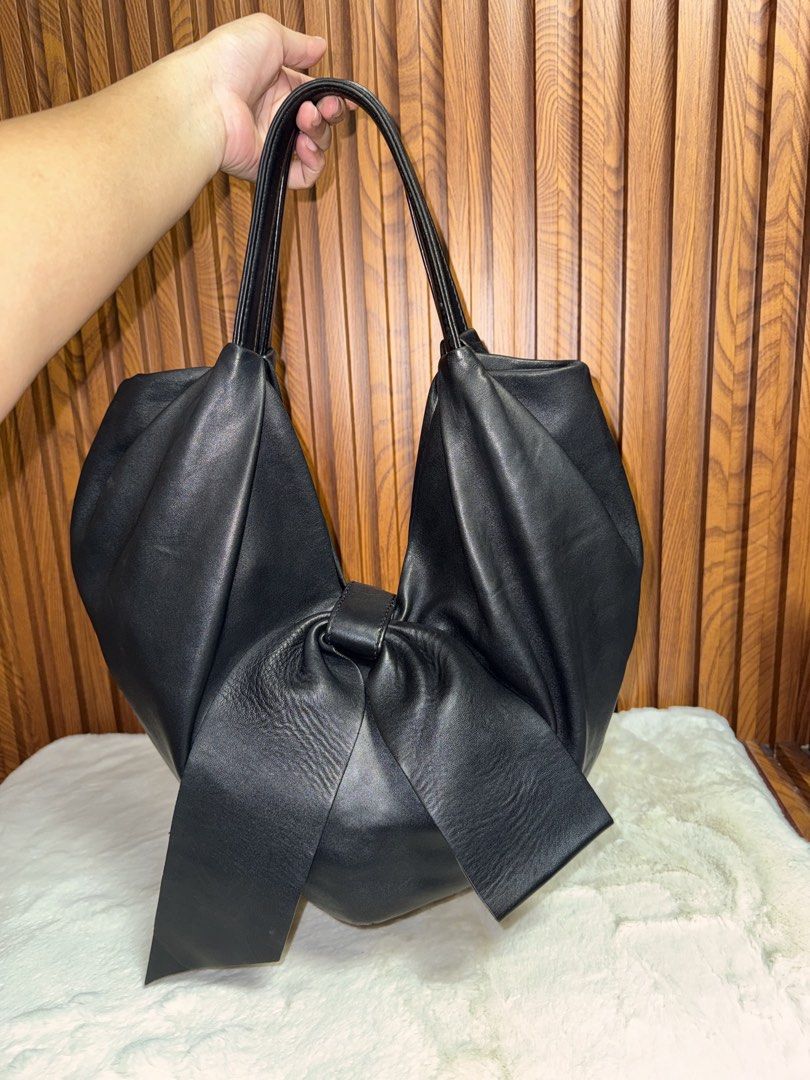 Authentic Valentino Black Leather Bow Tote Handbag (Category: Luxury Bags & Wallets) located in Subic. Submitted by luxshoppe88 (Listing ID 1466877441, Image 3). Description: Authentic Valentino black leather handbag featuring dual top handles, a chic front bow, and silver-tone logo hardware. The open-top design reveals a spacious textile interior complete with a zipper pocket and slip compartments. Soft, luxurious leather in a versatile deep bla