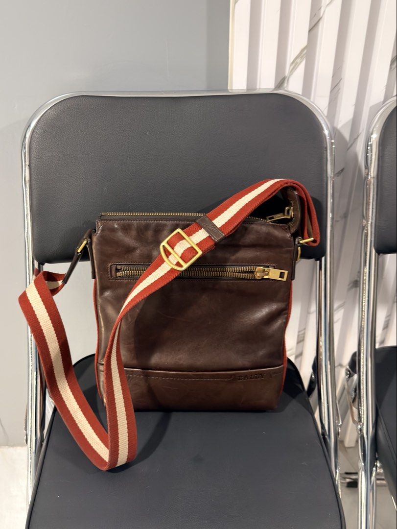 Bally Brown Leather Crossbody Bag (Category: Sling Bags) located in Quezon City. Submitted by houseoftrends_ (Listing ID 1466787090, Image 1). Description: Brown leather crossbody bag with distinctive red and white striped web strap. Gold-tone hardware throughout, including chunky double zippers on top and a zipped pocket on the front. Bally branding stamped on the leather and engraved on zipper pulls. Adjustable strap with metal buckle. Born in 