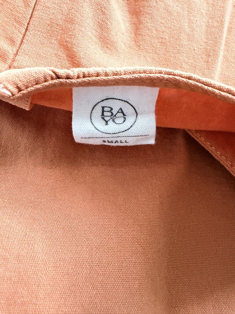 Bayo Orange Crop Top Small (Category: Sleeveless) located in Taguig. Submitted by mrs.k.see (Listing ID 1466845222, Image 2). Description: Orange sleeveless top from Bayo in size small. Boxy fit with textured woven patch details near the bottom hem. Split neckline with a hidden zip closure at the front. Simple, airy piece, easy to match with high-waisted shorts or skirts. Clean fabric, no stains or flaws noted..