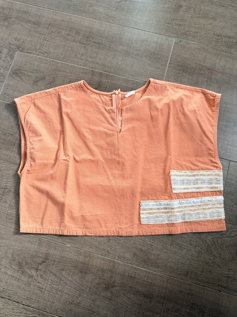 Bayo Orange Crop Top Small (Category: Sleeveless) located in Taguig. Submitted by mrs.k.see (Listing ID 1466845222, Image 1). Description: Orange sleeveless top from Bayo in size small. Boxy fit with textured woven patch details near the bottom hem. Split neckline with a hidden zip closure at the front. Simple, airy piece, easy to match with high-waisted shorts or skirts. Clean fabric, no stains or flaws noted..