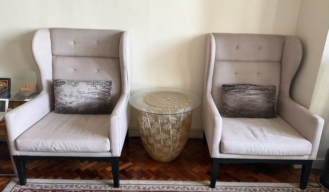 Beige Wingback Armchair with Accent Pillow (Category: Chairs) located in Makati City. Submitted by smanisha (Listing ID 1466819473, Image 2). Description: - Elegant beige fabric wingback armchair with classic tufted backrest - Includes a stylish patterned grey accent pillow - Solid black wooden legs (note: minor paint chips and scratches near the bottom, as shown in photos) - Extremely comfortable seating, ideal for a living room or reading corne