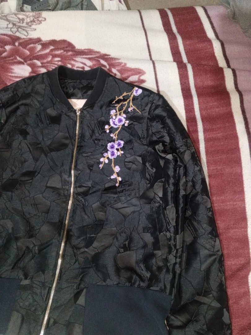 Black bomber jacket with floral embroidery (Category: Coats, Jackets and Outerwear) located in Baguio. Submitted by tyrontoler83676 (Listing ID 1466933957, Image 3). Description: - Color: Classic black - Design: Textured geometric pattern all over - Details: Eye-catching purple cherry blossom embroidery on the left chest - Hardware: Premium gold-tone front zip-up closure - Fit/Trim: Comfortable ribbed black cuffs and hem - Condition: Clean overal