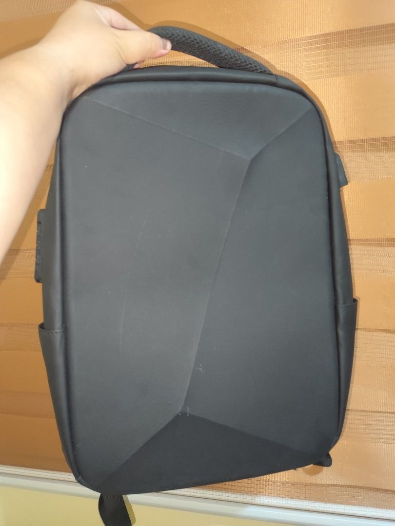 Black geometric hard-shell laptop backpack with multiple compartments (Category: Backpacks) located in Naga. Submitted by semflewer (Listing ID 1466832828, Image 1). Description: - Sleek black minimalist design with a structured geometric front panel - Comfortable daily wear with padded mesh back straps and back panel - Secure hidden zippered pocket on the back for valuables - Deep main compartment with practical side pockets - Reinforced top han