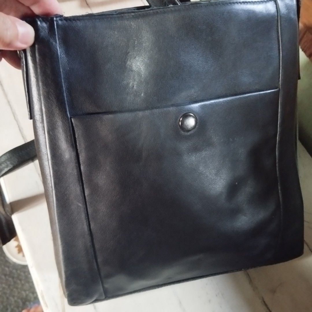 Black Leather Crossbody Bag (Category: Sling Bags) located in Manila. Submitted by lene48 (Listing ID 1466815786, Image 1). Description: - Color & Material: Black leather crossbody bag - Closure & Storage: Front pocket with button snap closure - Strap: Adjustable strap with metallic buckle hardware - Interior: Lined with a patterned fabric, includes a zippered compartment and a leather brand patch - Condition: Minor wear visible on the hardware a