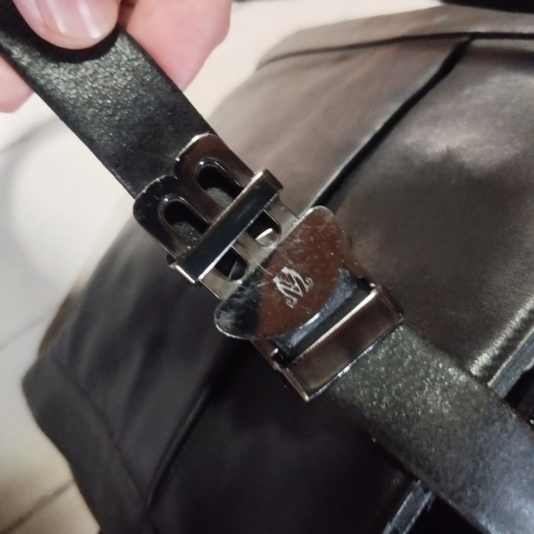 Black Leather Crossbody Bag (Category: Sling Bags) located in Manila. Submitted by lene48 (Listing ID 1466815786, Image 2). Description: - Color & Material: Black leather crossbody bag - Closure & Storage: Front pocket with button snap closure - Strap: Adjustable strap with metallic buckle hardware - Interior: Lined with a patterned fabric, includes a zippered compartment and a leather brand patch - Condition: Minor wear visible on the hardware a