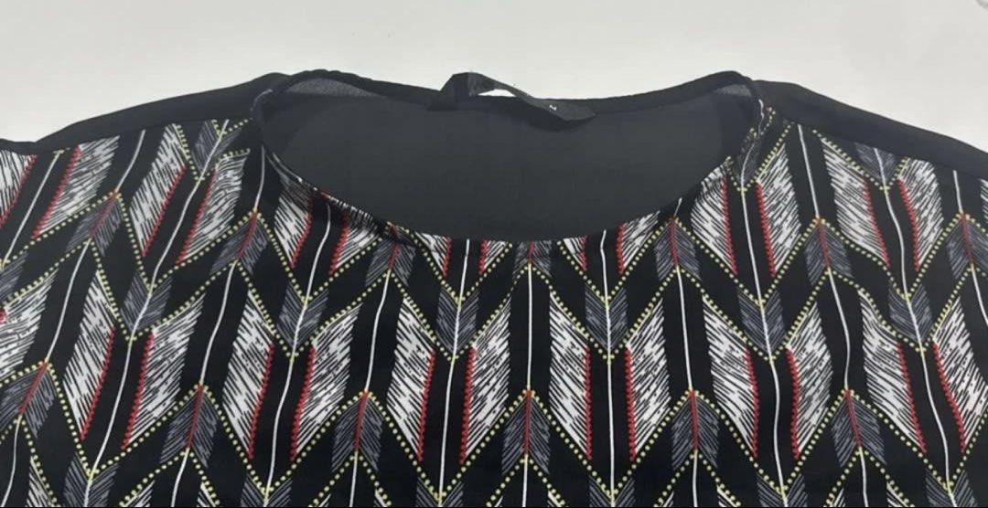 Black patterned sleeveless blouse size M (Category: Sleeveless) located in Pasay City. Submitted by szepter (Listing ID 1466793671, Image 3). Description: - Black sleeveless blouse with a striking tribal arrow front panel - Size: Medium (tag attached) - Fit: Relaxed with a flattering scoop neckline and longer back hem - Material: Lightweight, airy chiffon-like fabric - Styling: Perfect for effortless everyday wear with jeans or trousers.
