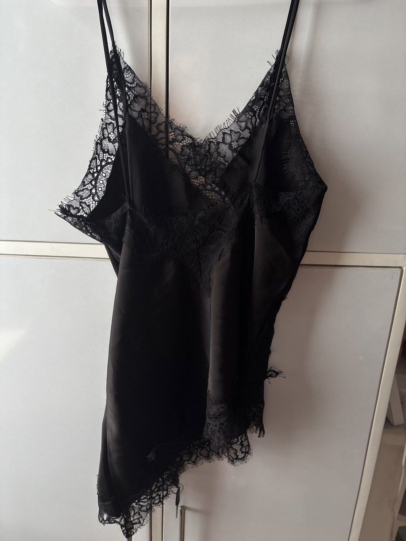 Black silk camisole with lace trim (Category: Sleeveless) located in Manila. Submitted by jodi.declutters (Listing ID 1466781209, Image 3). Description: - Color: Black with smooth, silky finish and slight sheen - Design: V-neckline, sides, and asymmetrical hem detailed with delicate floral lace trim - Straps: Adjustable thin spaghetti straps for a custom fit - Styling: Versatile piece, great for pairing with jeans or a skirt for a night out - Con