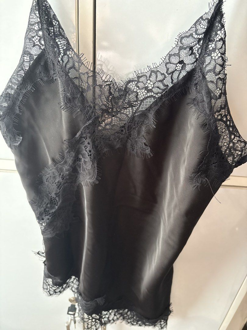 Black silk camisole with lace trim (Category: Sleeveless) located in Manila. Submitted by jodi.declutters (Listing ID 1466781209, Image 2). Description: - Color: Black with smooth, silky finish and slight sheen - Design: V-neckline, sides, and asymmetrical hem detailed with delicate floral lace trim - Straps: Adjustable thin spaghetti straps for a custom fit - Styling: Versatile piece, great for pairing with jeans or a skirt for a night out - Con