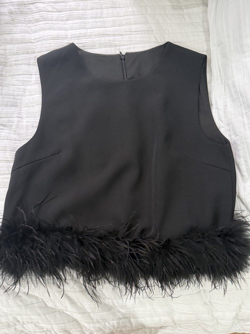 Black sleeveless top with feather hem (Category: Sleeveless) located in Quezon City. Submitted by afternoonstore (Listing ID 1466841991, Image 1). Description: - Color: Black - Style: Sleeveless top with round neckline - Closure: Back collar zipper - Feature: Soft feather trim along the bottom hemline and neat bust darts for a flattering fit - Occasion: Perfect for parties and evening outings - Pairing: Great with high-waisted trousers or skirts.