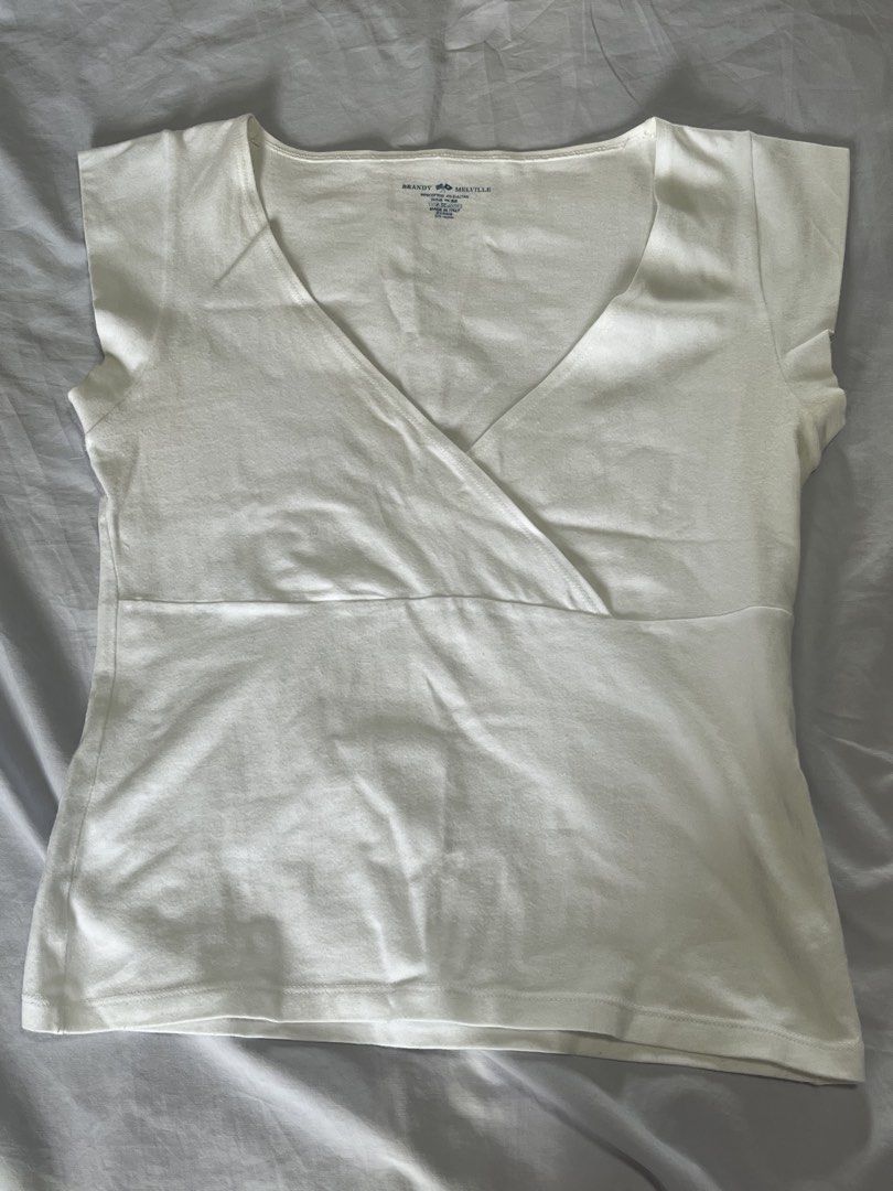 Brandy Melville White Amara Top (Category: Blouses) located in Manila. Submitted by aaa0ki (Listing ID 1466788008, Image 1). Description: Brandy Melville Amara Top - Condition: good, no issues or stains - Color: Classic White - Material: 96% cotton, 4% elastane - Fit: Fitted cut with a wrap-around V-neckline - Perfect for effortless, everyday styling love this top so much ! very flattering and a good elevated basic ☺️💕.