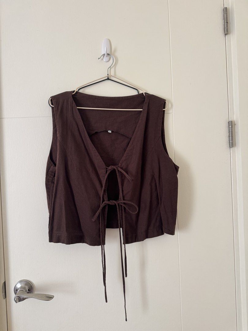 Brown tie-front crop vest top 2XL (Category: Sleeveless) located in Mandaluyong City. Submitted by trinket.ph (Listing ID 1466774933, Image 1). Description: - Color: Dark brown - Size: 2XL - Design: Deep V-neck, double front string ties, and back collar cutout - Material: Light and breathable fabric - Versatility: Perfect for layering over tees or wearing on its own - Condition: Good overall condition, no damage or stains.