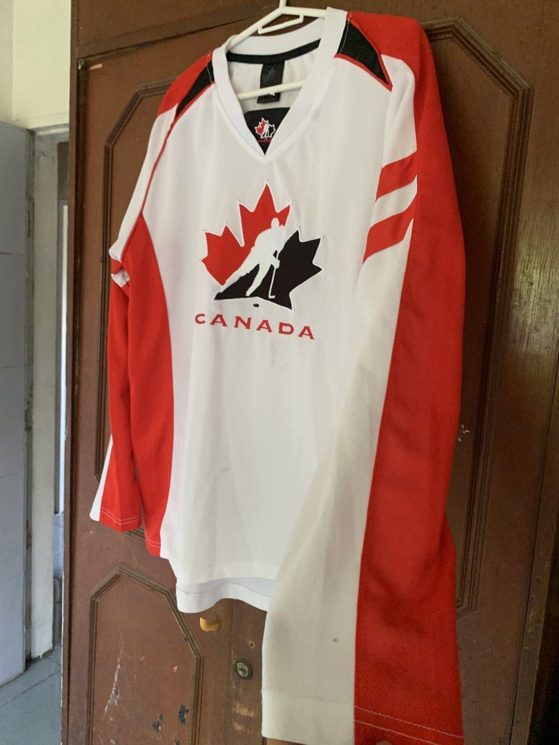 Canada Hockey Jersey Red White (Category: Activewear) located in Tarlac. Submitted by durkk4ever (Listing ID 1466890055, Image 2). Description: - Authentic Team Canada hockey jersey in striking red, white, and black - Bold front hockey player graphic with "Canada" lettering - Classic V-neck collar with black trim and stylish striped sleeves - Official tag detail on the bottom hem - A must-have for hockey fans and sports memorabilia collectors.