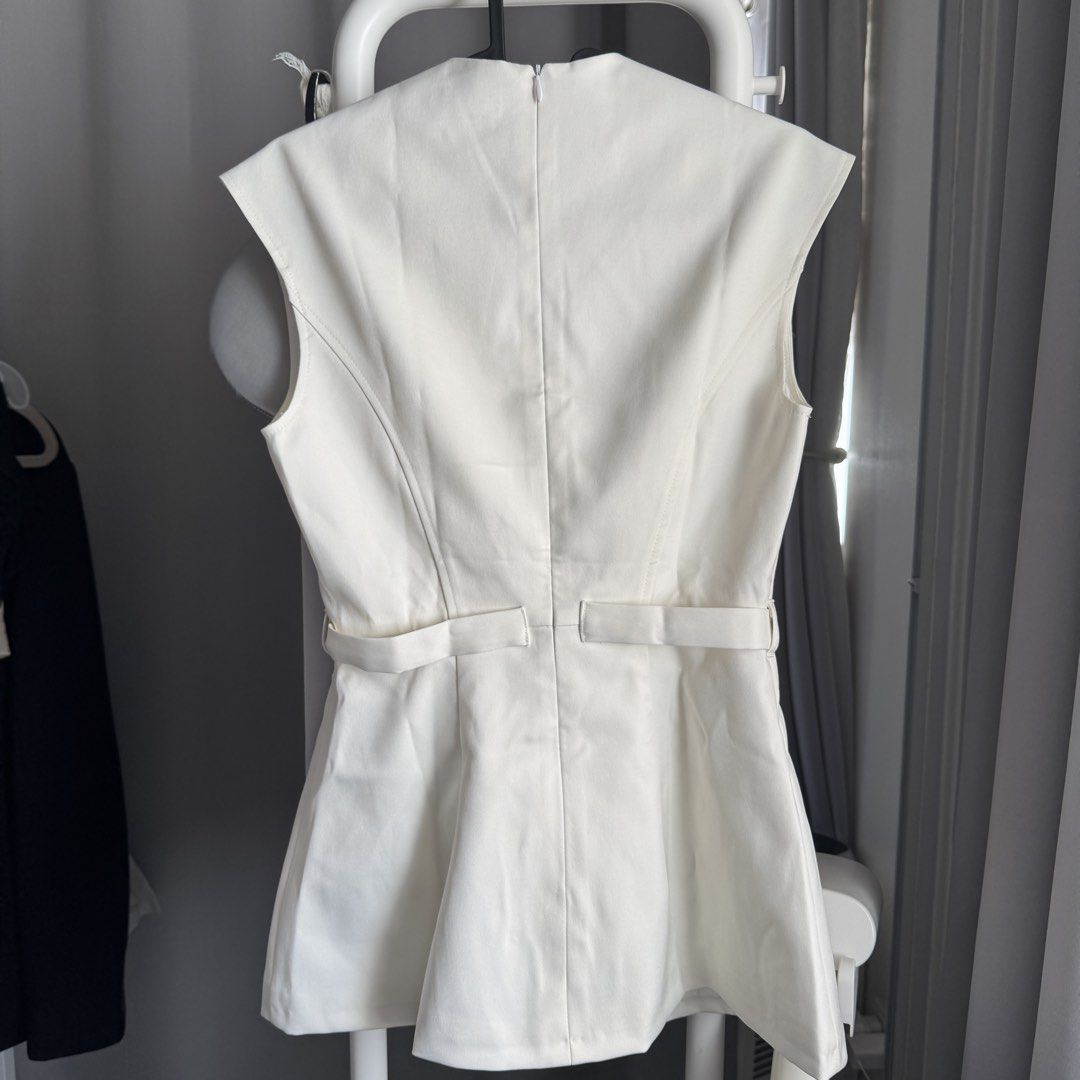 Celes White Top Size S BNWT (Category: Sleeveless) located in Quezon City. Submitted by averioph (Listing ID 1466783572, Image 3). Description: - Brand: Celes - Color: Cream White - Size: S (Small) - Condition: Brand new with original retail tags attached - Design: Sleeveless V-neck with gold-tone front buttons - Details: Includes a matching waist belt with a gold buckle, a back zipper closure, and double lined - Style: Chic, elegant, and versati