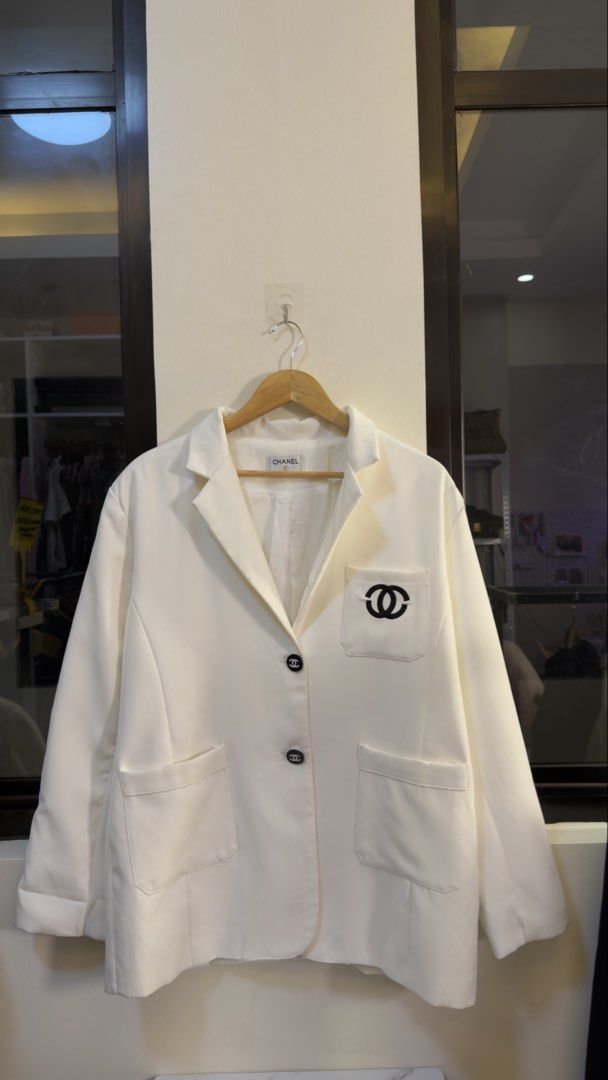 Chanel White Blazer with Black CC Logo Pocket (Category: Coats, Jackets and Outerwear) located in Paranaque City. Submitted by mykapoynton (Listing ID 1466958420, Image 2). Description: Chanel White Blazer with Black CC Logo Pocket - Design: Classic lapel collar with a two-button front closure - Pockets: Two functional front patch pockets - Interior: Fully lined with white fabric and features the official Chanel brand label at the back neck - Sle