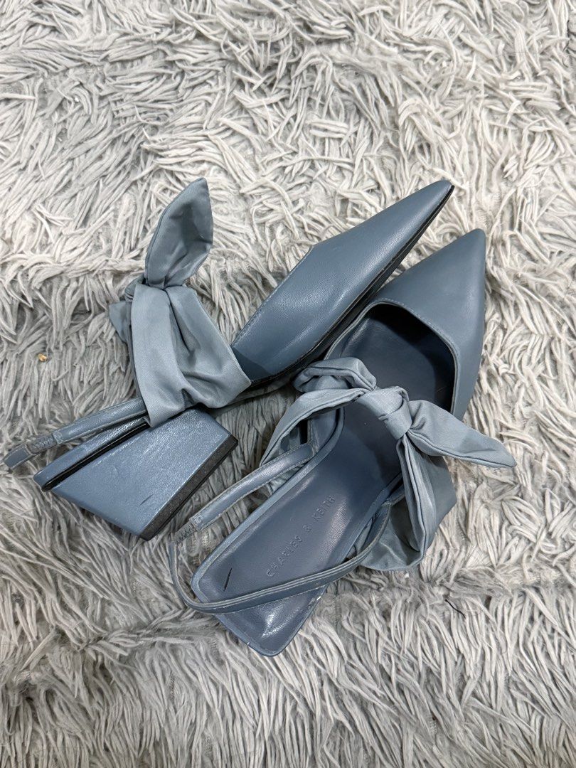 Charles & Keith Blue Bow Slingback Heels (Category: Heels) located in Taguig. Submitted by shabbydoo13 (Listing ID 1466797167, Image 2). Description: - Brand: Charles and Keith - Style: Pointed-toe slingback heels with a stable thick block design - Color: Light blue - Detail: Charming fabric bow tied at the front - Fit: Adjustable strap at the back for a secure fit - Finish: Smooth outer material with a clean inner lining and stamped logo.