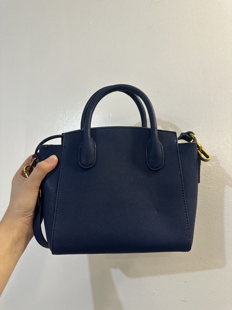 Charles & Keith Navy Blue Handbag with Strap (Category: Luxury Bags & Wallets) located in Makati City. Submitted by cosmicfire.4ba272 (Listing ID 1466929123, Image 3). Description: - Brand: Charles & Keith - Style: Structured handbag with dual top handles and detachable shoulder strap - Color: Classic navy blue with elegant gold hardware accents - Material: Clean pebbled faux leather with secure zipped main compartment - Condition: Good, with a m