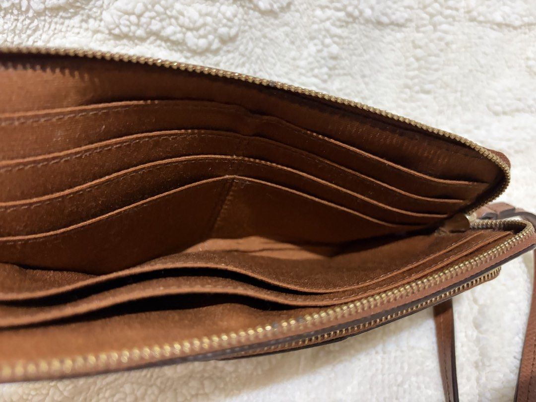 Coach Signature Canvas Double Zip Wristlet (Category: Luxury Bags & Wallets) located in Paranaque City. Submitted by greatfinds108 (Listing ID 1466811945, Image 3). Description: - Brand: Coach - Material: Signature canvas with smooth brown leather center stripe - Hardware: Gold-tone - Compartments: Dual zippered sections for phone, cards, and cash - Interior: Brown fabric lining with multiple card slots and slip pockets - Extras: Includes a conve