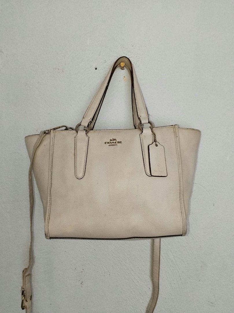 Coach White Leather Tote Shoulder Bag (Category: Luxury Bags & Wallets) located in Manila. Submitted by bagelyascollection (Listing ID 1466827298, Image 1). Description: White pebbled leather Coach handbag with gold hardware. Includes top handles and a detachable shoulder strap. Interior lined with fabric featuring Coach logo print, plus interior zip pocket. Hangtag attached to the side. Exterior shows some discoloration and scuffs. Interior has 