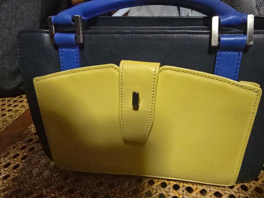 Colorblock leather handbag yellow blue black (Category: Luxury Bags & Wallets) located in San Fernando. Submitted by banings (Listing ID 1466797774, Image 1). Description: - Vibrant colorblock design in yellow, blue, and black leather - Structured silhouette with a secure front flap closure - Stylish blue handles accented with silver-toned hardware - Neat, clean stitching throughout the bag - Spacious interior with plenty of room for daily essent