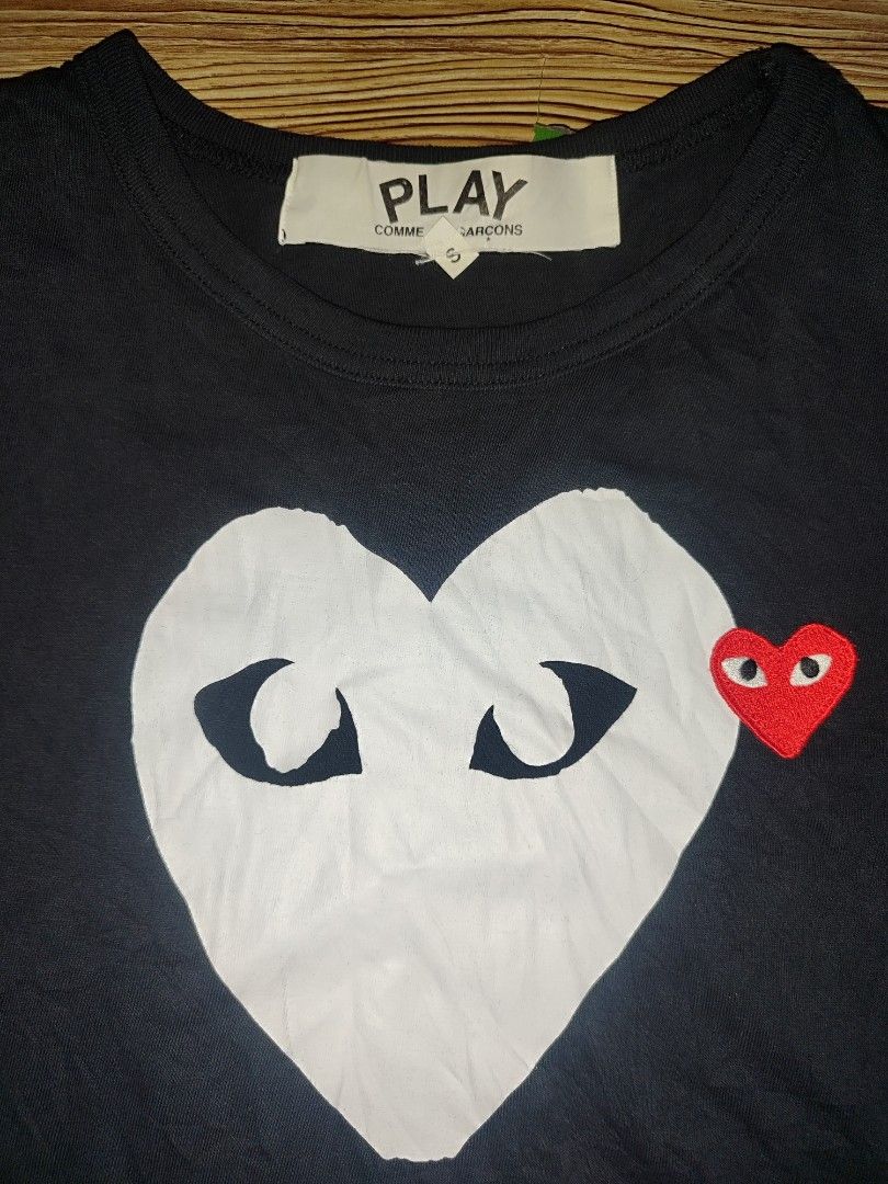 COMME des GARÇONS PLAY Black Heart Tee Size S (Category: Shirts) located in Davao. Submitted by valeriajan24414 (Listing ID 1466847549, Image 2). Description: - Brand: COMME des GARÇONS PLAY - Size: S - Material: 100% Cotton - Origin: Made in Japan - Design: Large white heart graphic with signature embroidered red heart patch - Details: Classic crew neck, short sleeves, model code AZ-T116 - Collection: AD2017 tag inside - Condition: 100% authenti