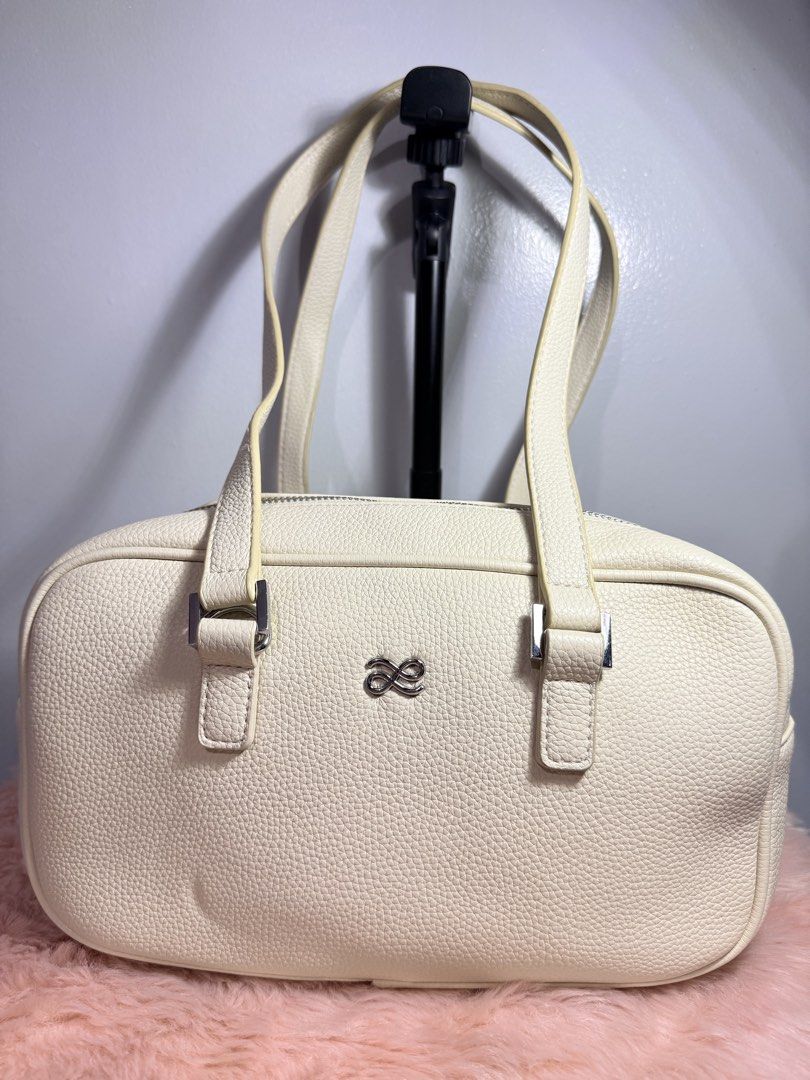 Cream Pebble Leather Shoulder Bag Tote (Category: Shoulder Bags) located in Quezon City. Submitted by shaberbree (Listing ID 1466907320, Image 1). Description: - Material: Cream textured pebble leather - Hardware: Silver-tone - Design: Structured rectangular shape with dual top carry handles - Closure: Top zip closure - Interior: Beige fabric-lined with 1 zipper pocket and open slip pockets - Branding: Subtle metallic ribbon/bow logo emblem on th