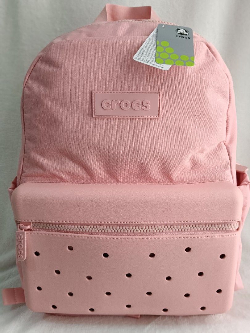 Crocs Pink Backpack (Category: Backpacks) located in Quezon City. Submitted by shinereign (Listing ID 1466843716, Image 1). Description: - Brand new with tags attached - Iconic pink Crocs design with ventilation holes on the front pocket - Crocs logo patch detailing - Adjustable padded shoulder straps with breathable mesh backing - Convenient top grab handle - Spacious main compartment equipped with extra storage pockets.