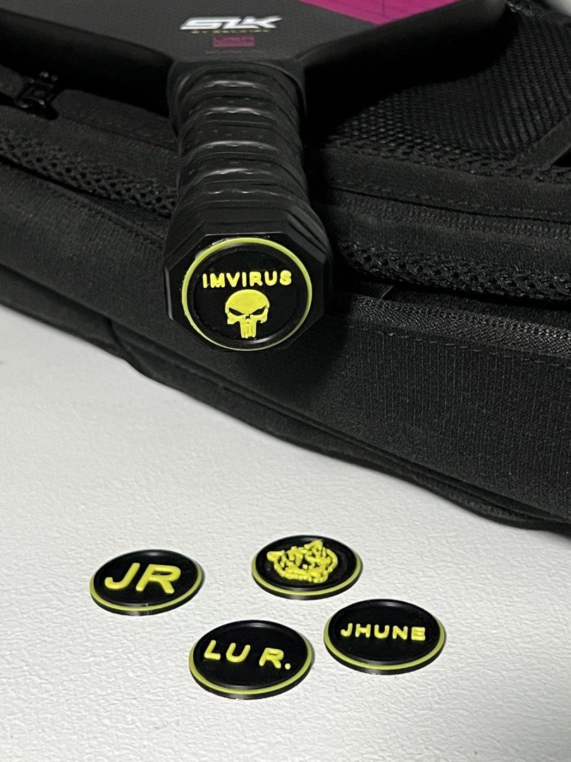 Custom 3D Printed Pickleball Paddle Butt Cap/End Cap (Category: Racket and Ball Sports) located in Marikina City. Submitted by johnurbina (Listing ID 1466903417, Image 1). Description: Custom 3D printed butt caps for pickleball paddles. Includes personalized inserts featuring names like IMVIRUS, JR, LU R., and JHUNE alongside a skull logo design. Black base with vibrant yellow raised lettering. Great way to customize your gear and tell your paddl