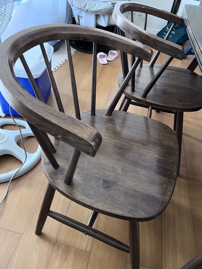 Dining table set with glass top and 4 chairs (Category: Tables & Sets) located in Manila. Submitted by this_is_my_closet (Listing ID 1466852527, Image 3). Description: Wooden dining table with protective glass top, measuring a standard rectangular size. Includes four matching dark wood chairs in two different styles. Two chairs feature curved wooden armrests and spindle backs. The other two have rounded wooden seats and black metal legs with curv