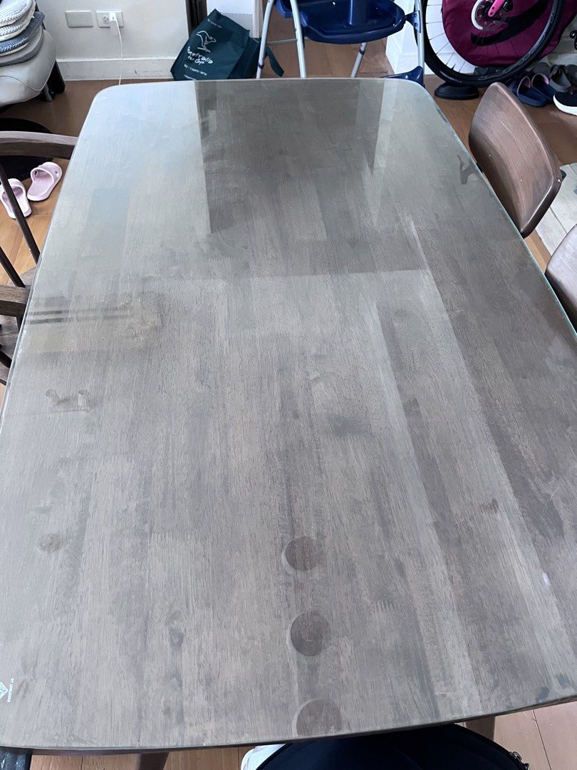 Dining table set with glass top and 4 chairs (Category: Tables & Sets) located in Manila. Submitted by this_is_my_closet (Listing ID 1466852527, Image 2). Description: Wooden dining table with protective glass top, measuring a standard rectangular size. Includes four matching dark wood chairs in two different styles. Two chairs feature curved wooden armrests and spindle backs. The other two have rounded wooden seats and black metal legs with curv