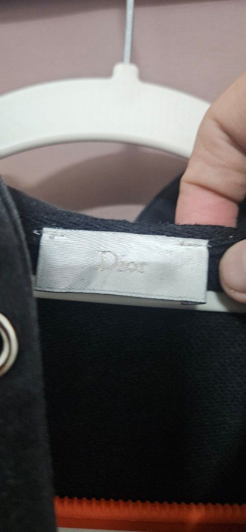 Dior Black Zip-Up Hoodie (Category: Hoodies) located in Santa Maria. Submitted by rommelmateo (Listing ID 1466946623, Image 3). Description: Dior black zip-up hoodie with front pockets. Has a bee embroidery detail on the sleeve and a branded leather tag at the bottom hem with a button closure. Ribbed cuffs and hem. Full zip front with hood. Washed black look with some fading and wear..