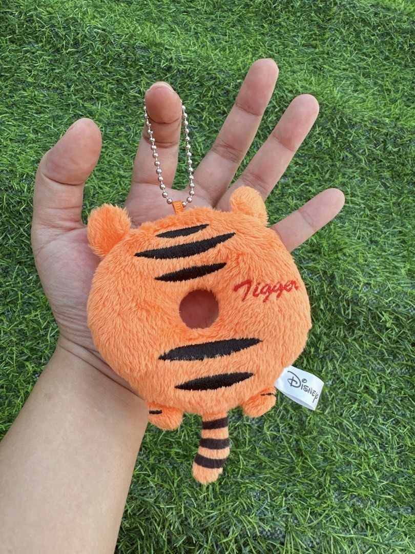 Disney Tigger Donut Plush Keychain Bag Charm (Category: Plushies & Soft Toys) located in Manila. Submitted by ronoarabbit.ph (Listing ID 1466873263, Image 1). Description: - Authentic Disney Tigger plush keychain shaped like a sweet donut - Features bright orange fabric with embroidered black tiger stripes and Tigger's signature - Detailed with cute little ears, a striped tail, and a secure ball chain - Official Disney tag attached; Made in China