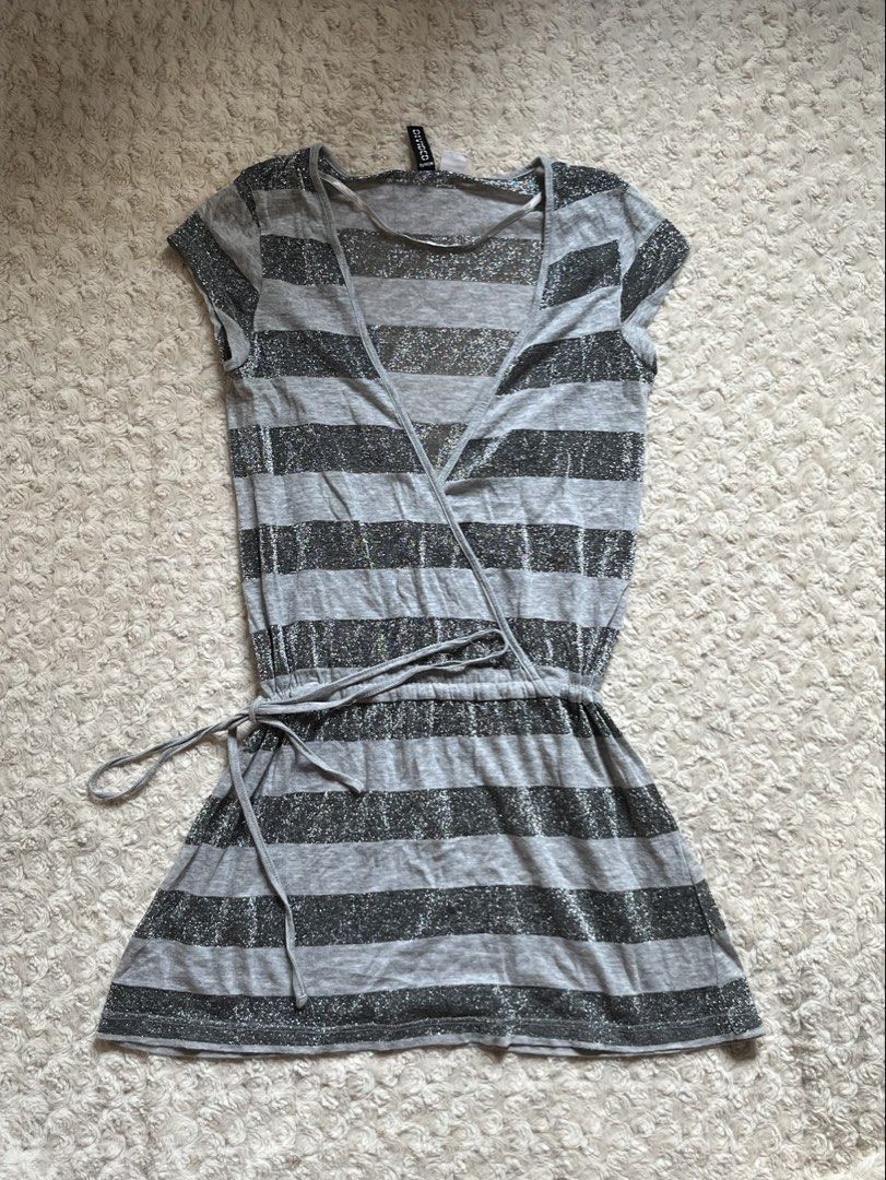 Divided by H&M Grey Striped Sparkle Tie Top (Category: Dresses) located in Mandaluyong City. Submitted by namislounge (Listing ID 1466928545, Image 1). Description: Fits xs-small - Style: Grey & black striped wrap dress with subtle metallic silver sparkle - Design: V-neck front, short cap sleeves, adjustable drawstring waist - Fabric: Lightweight knit with stylish sheer panels on top - Made in Turkey - Condition: Great piece for casual nights out
